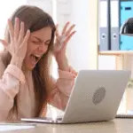 Business owner in front of her computer feeling frusterated.