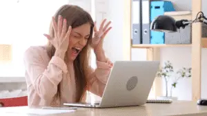 Business owner in front of her computer feeling frusterated.